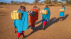 African women from Maasai tribe carrying water to their village, Kenya, Africa.