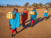 African women from Maasai tribe carrying water to their village, Kenya, Africa.
