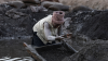 A woman collects cobalt and copper using a homemade tool in a muddy pit at an artisanal mine site on May 25, 2025 in Kolwezi, Democratic Republic of Congo.