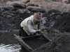 A woman collects cobalt and copper using a homemade tool in a muddy pit at an artisanal mine site on May 25, 2025 in Kolwezi, Democratic Republic of Congo.