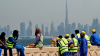 Workers sit on a wall against the backdrop of the city skyline as they take a break in Dubai on March 11, 2026. The oil-rich Gulf has borne the brunt of Iran's attacks in response to US-Israeli strikes that sparked the Middle East war, with Tehran targeting US assets but also civilian infrastructure.