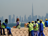 Workers sit on a wall against the backdrop of the city skyline as they take a break in Dubai on March 11, 2026. The oil-rich Gulf has borne the brunt of Iran's attacks in response to US-Israeli strikes that sparked the Middle East war, with Tehran targeting US assets but also civilian infrastructure.
